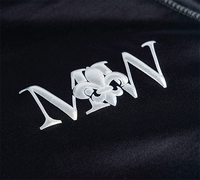 Metallic silver puff vinyl design on black fabric, featuring a raised and textured logo with a glossy finish.