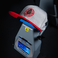 Close-up of 360 IQ® Hat Press in use, pressing a custom gray and red cap with precision temperature and time settings visible.